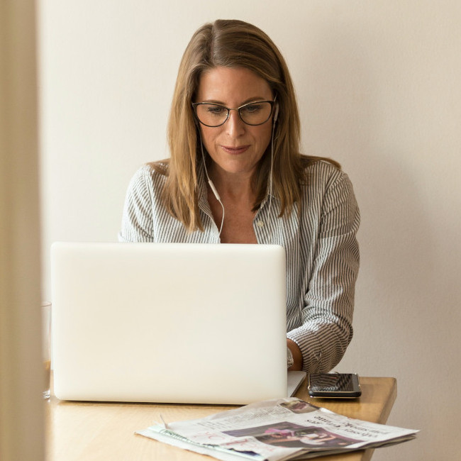 Žena s brýlemi, pracující v kanceláři za notebookem